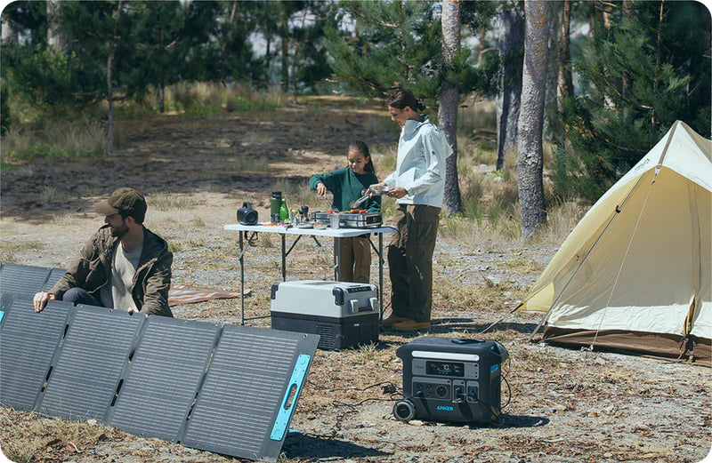 People camping outdoors with a solar panel and generator in a forest setting.