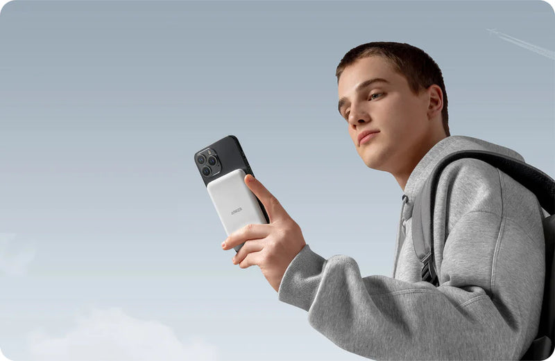 Person holding a smartphone with a clear blue sky background